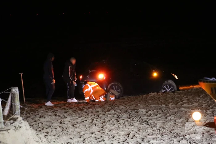 Automobilist rijdt auto vast op strand