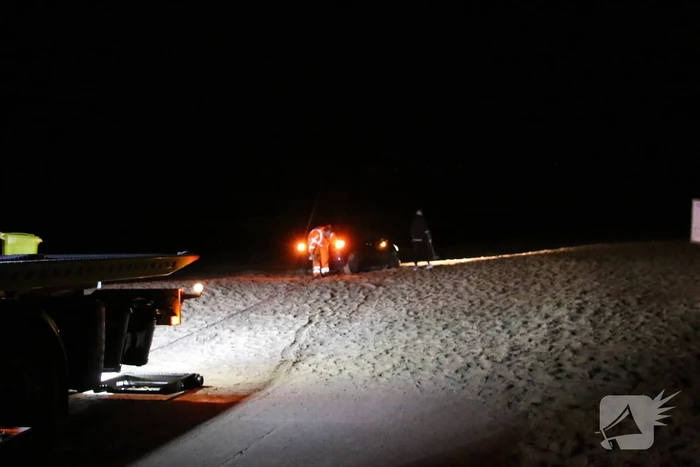 Automobilist rijdt auto vast op strand