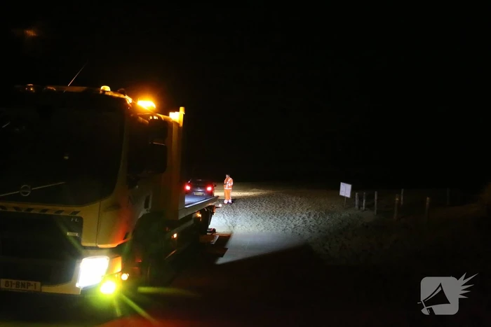 Automobilist rijdt auto vast op strand