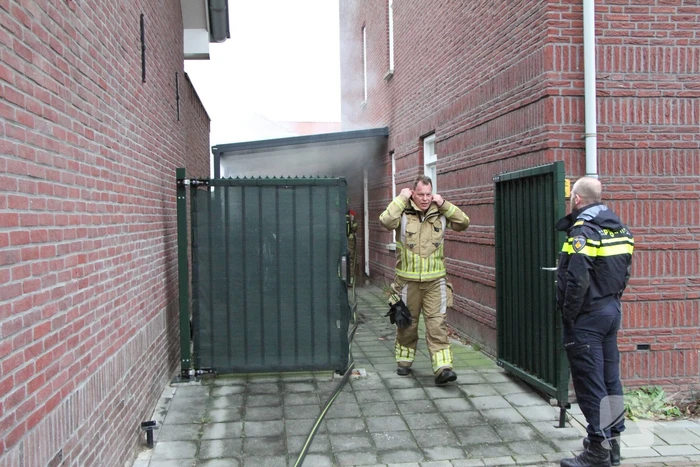 Brand onder overkapping van woning