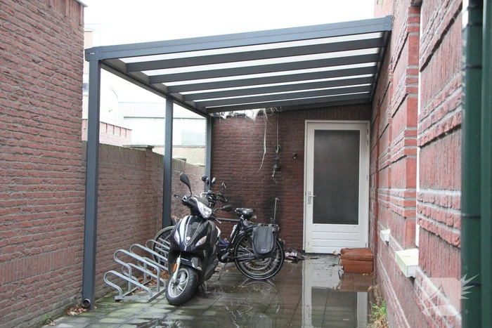 Brand onder overkapping van woning