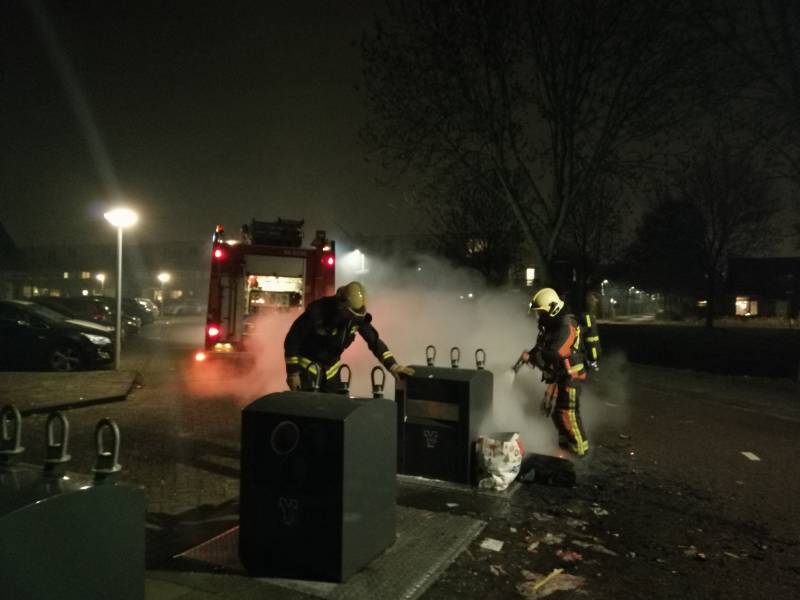 Vuurwerkresten in de brand naast papiercontainer