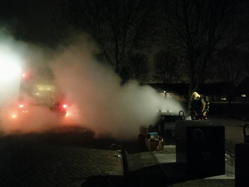 Vuurwerkresten in de brand naast papiercontainer