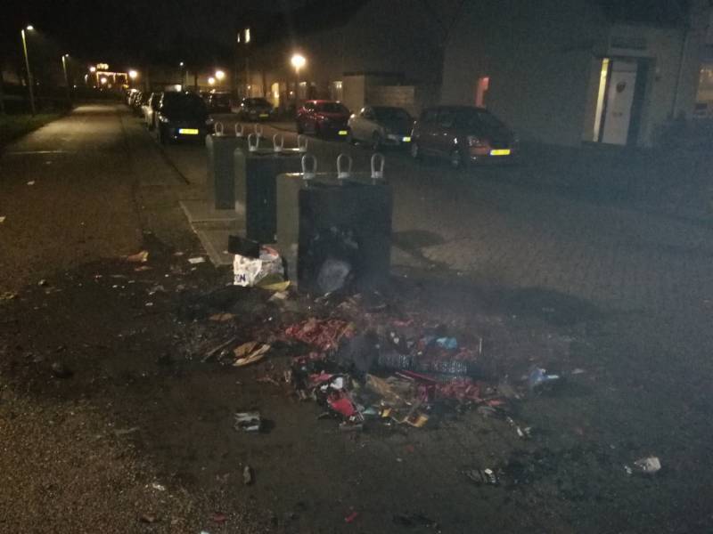 Vuurwerkresten in de brand naast papiercontainer