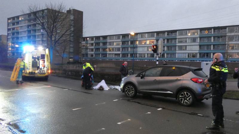 Personenauto schept wielrenner