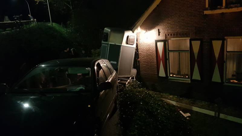 Auto met paardentrailer botst tegen huis.