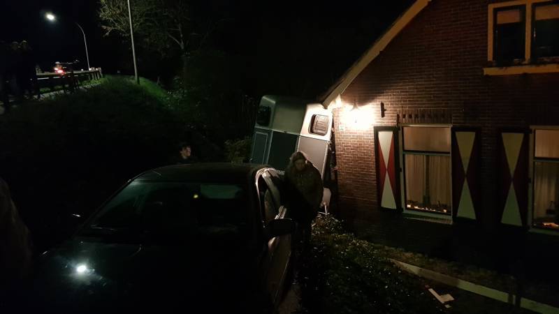 Auto met paardentrailer botst tegen huis.