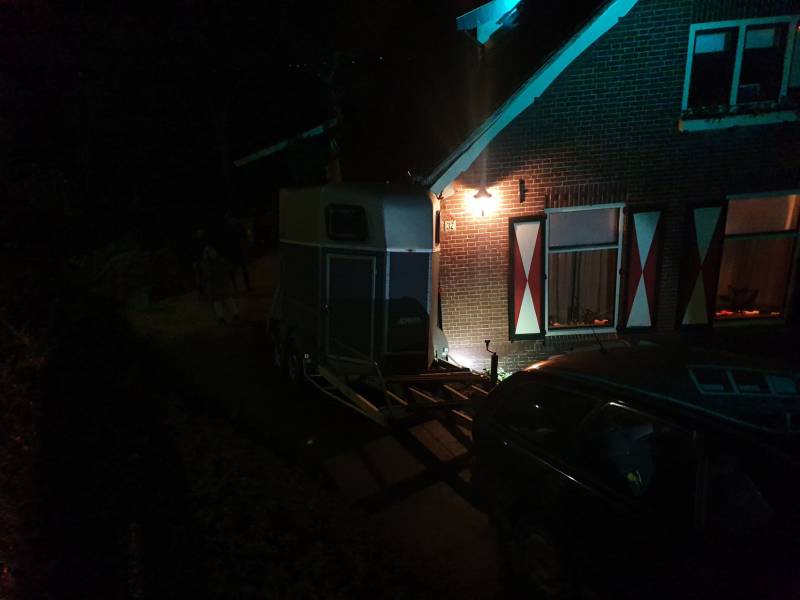 Auto met paardentrailer botst tegen huis.
