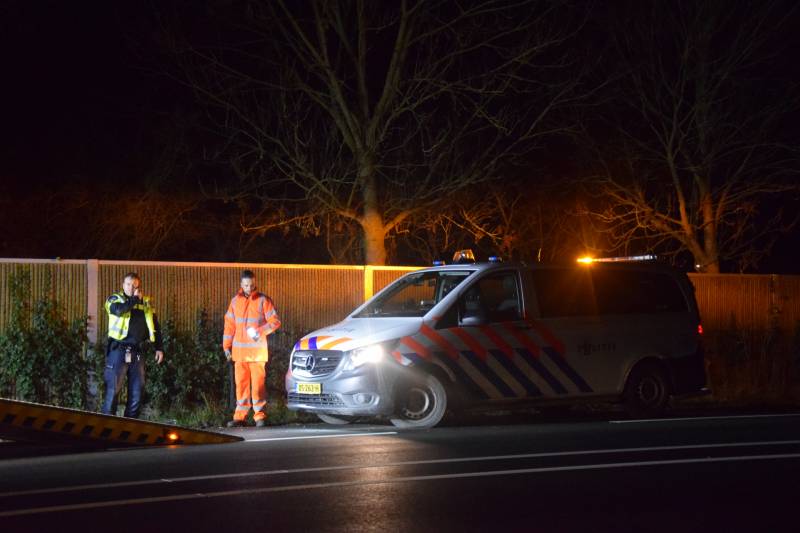 Politieauto en personenauto beschadigd door stenen op rijbaan