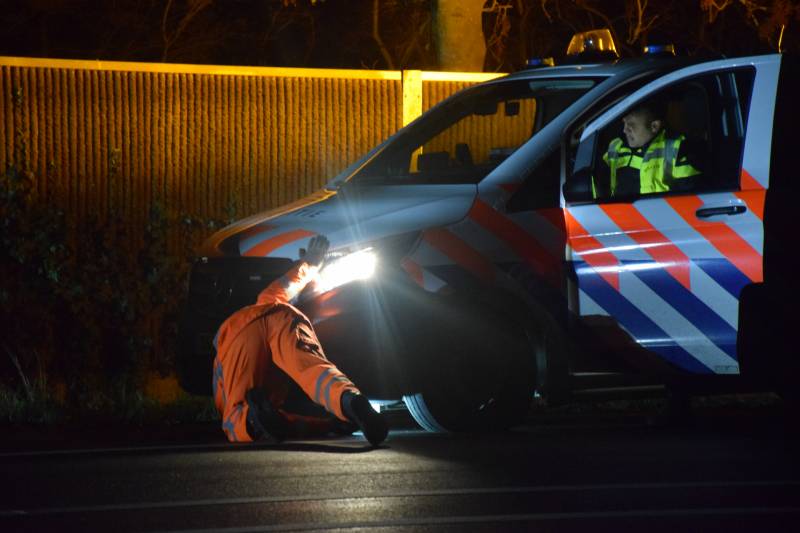 Politieauto en personenauto beschadigd door stenen op rijbaan