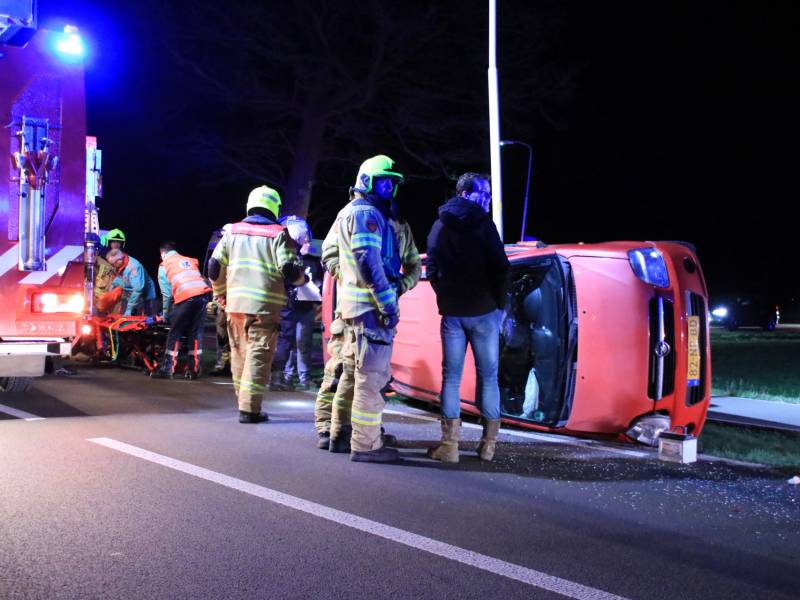 Auto op zijn kant na botsing tegen lantarenpaal