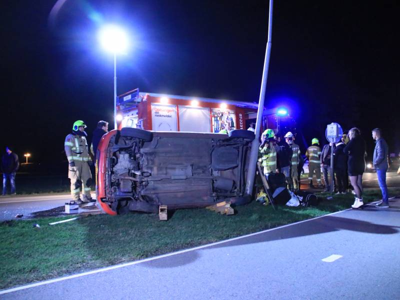 Auto op zijn kant na botsing tegen lantarenpaal
