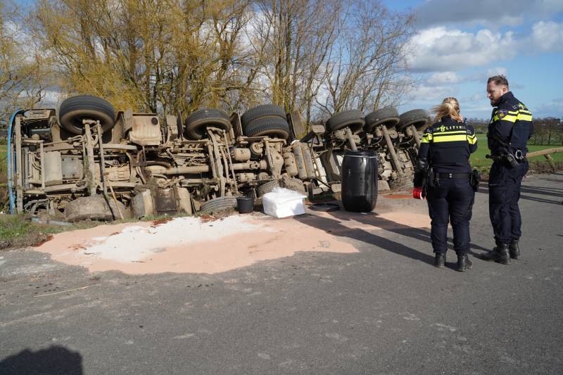 Vrachtwagen met zand van dijk gekanteld