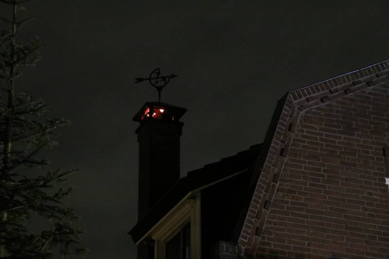 Vlammen slaan uit schoorsteen van woning