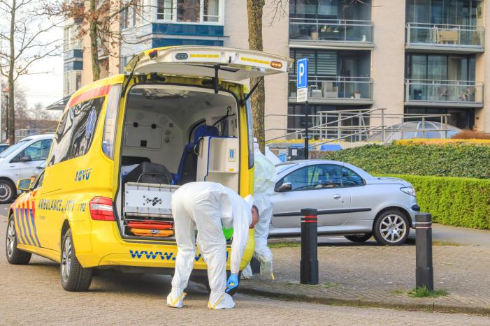 Mannen in witte pakken halen vermoedelijke coronapatiënt uit huis
