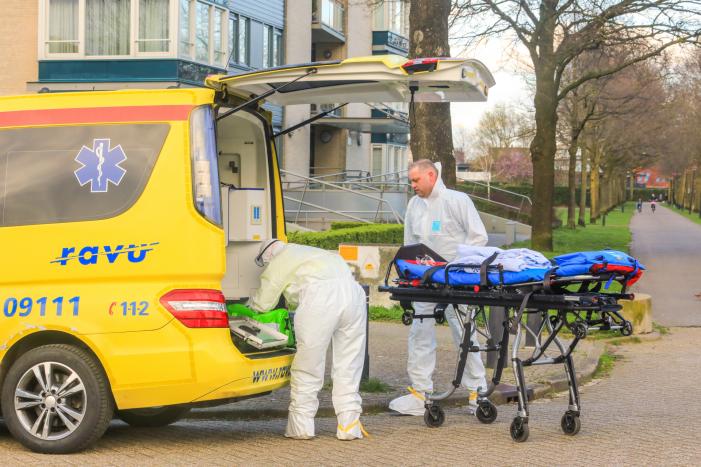 Mannen in witte pakken halen vermoedelijke coronapatiënt uit huis
