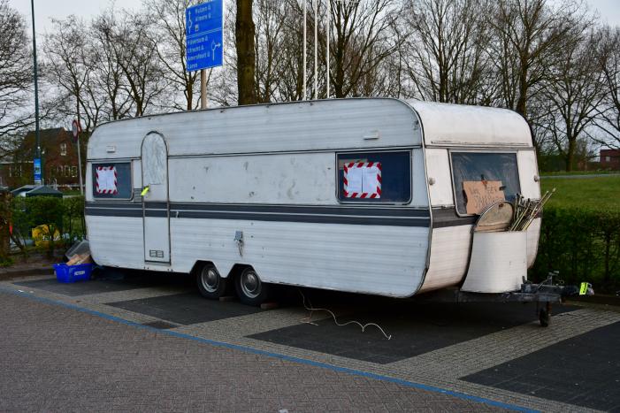 Handhaving sleept caravan met protesttekst weg van parkeerterrein gemeentewerf