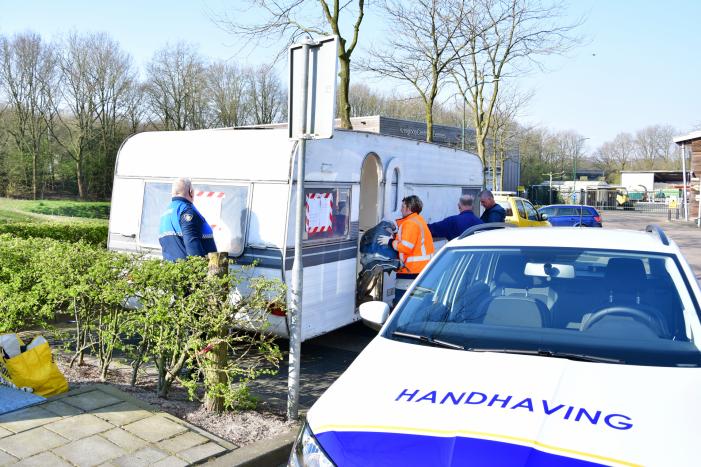 Handhaving sleept caravan met protesttekst weg van parkeerterrein gemeentewerf