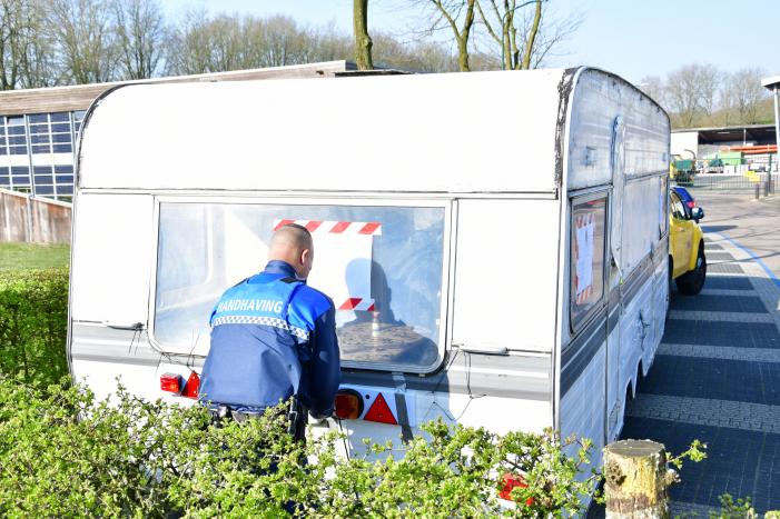Handhaving sleept caravan met protesttekst weg van parkeerterrein gemeentewerf