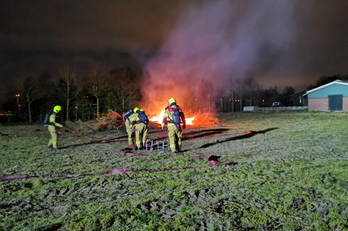 Berg met takken in weiland vatte vlam