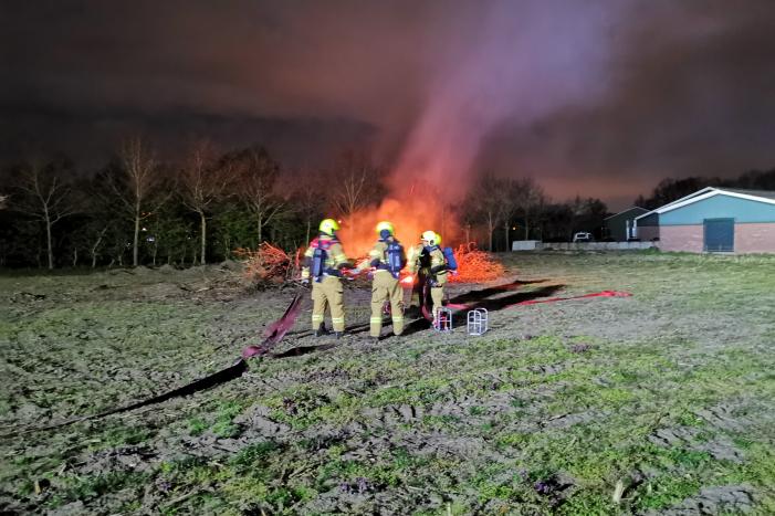 Berg met takken in weiland vatte vlam