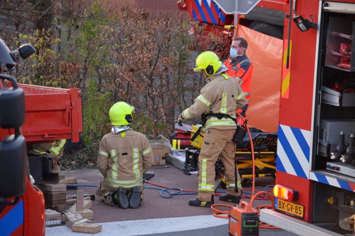 Man bekneld onder as van bedrijfswagen