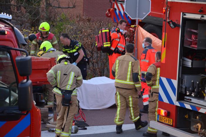 Man bekneld onder as van bedrijfswagen
