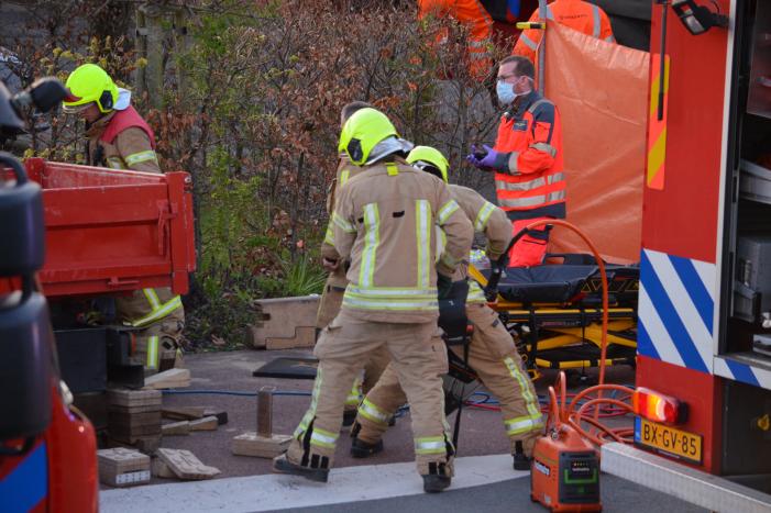 Man bekneld onder as van bedrijfswagen