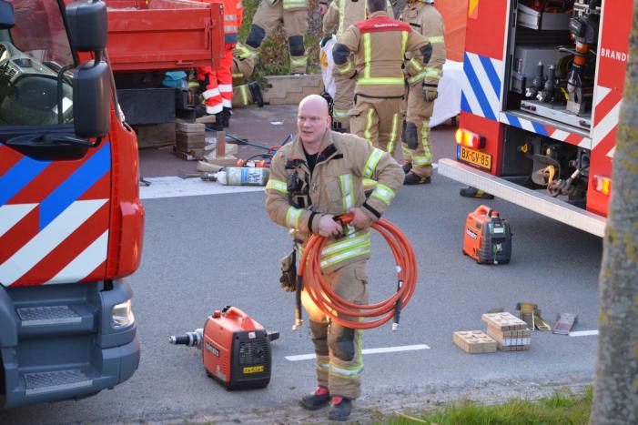 Man bekneld onder as van bedrijfswagen