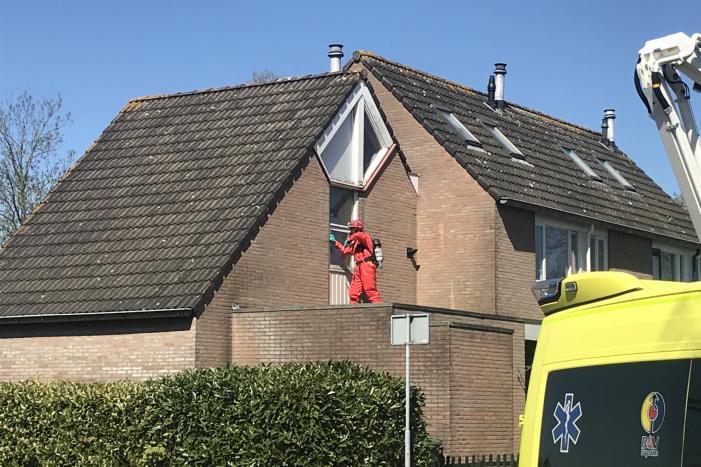 Brandweer in beschermende pakken halen persoon uit woning