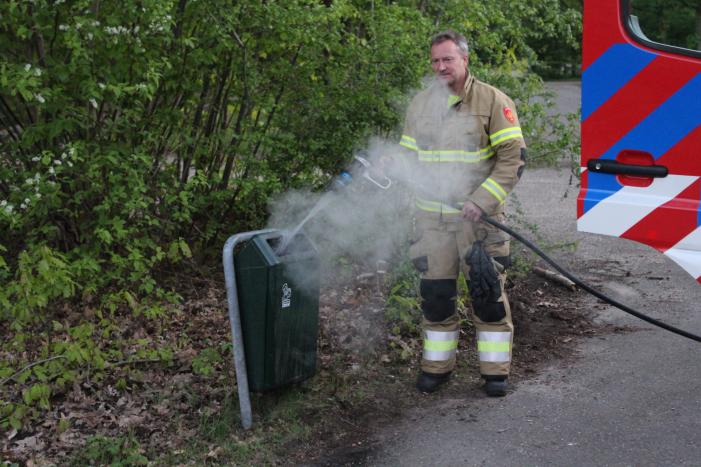 Omstanders doven vuur in prullenbak op parkeerterrein
