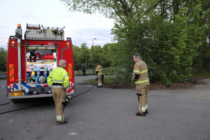 Omstanders doven vuur in prullenbak op parkeerterrein
