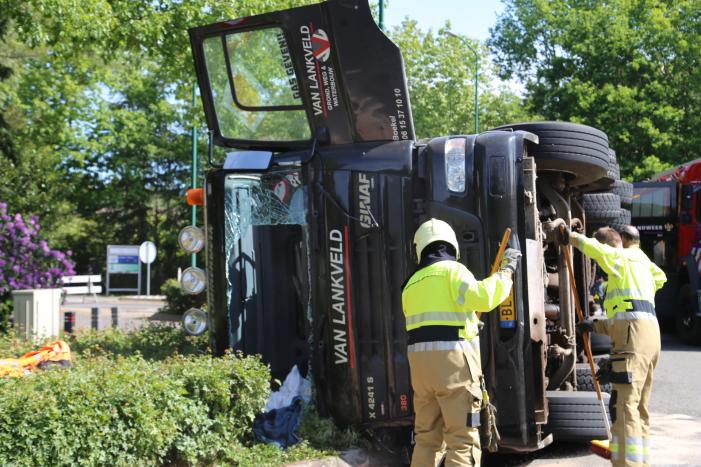 Vrachtwagen met tuinafval gekanteld op rotonde