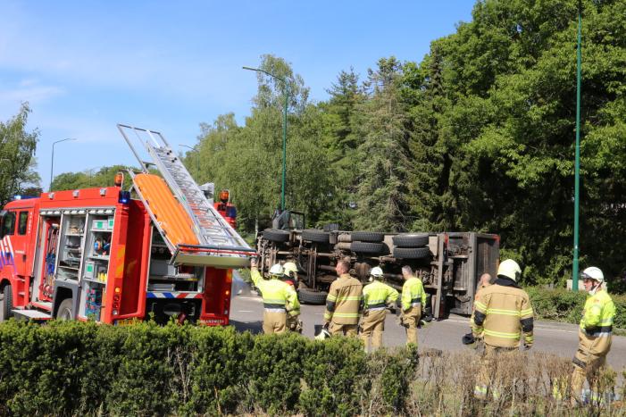 Vrachtwagen met tuinafval gekanteld op rotonde