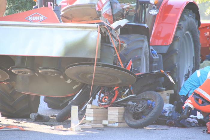 Scooter en scooterrijder bekneld onder tractor na ongeval