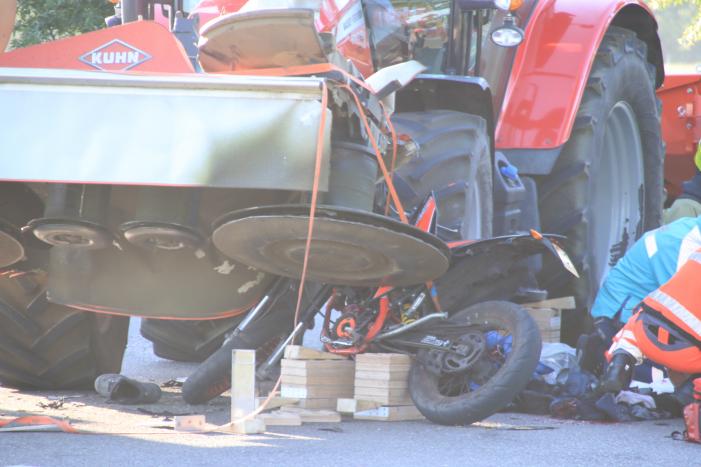 Scooter en scooterrijder bekneld onder tractor na ongeval
