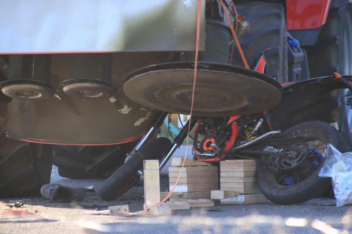 Scooter en scooterrijder bekneld onder tractor na ongeval