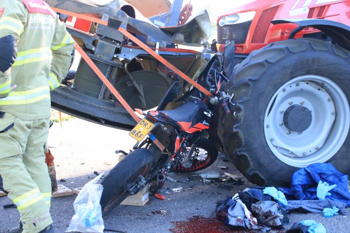 Scooter en scooterrijder bekneld onder tractor na ongeval