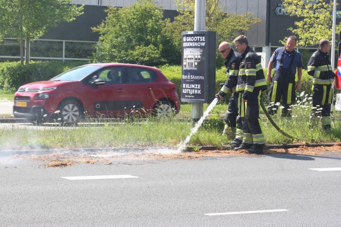 Brandweer blust brandend gras in berm