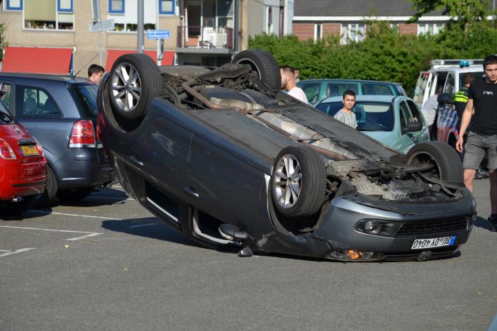 Auto op zijn kop na aanrijding met geparkeerde auto