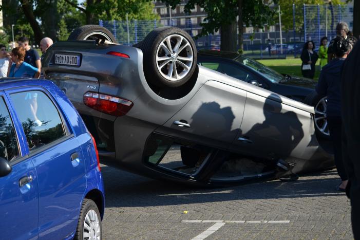 Auto op zijn kop na aanrijding met geparkeerde auto