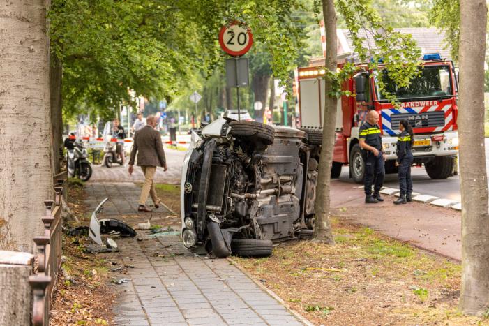 Auto crasht belandt op zijkant, bestuurder slaat op de vlucht