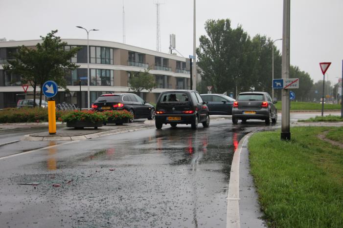 Boodschappenbus klapt achterop auto voor rotonde