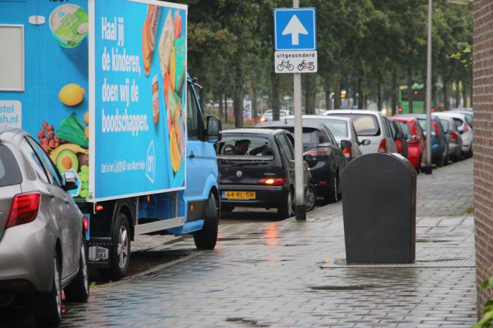 Boodschappenbus klapt achterop auto voor rotonde