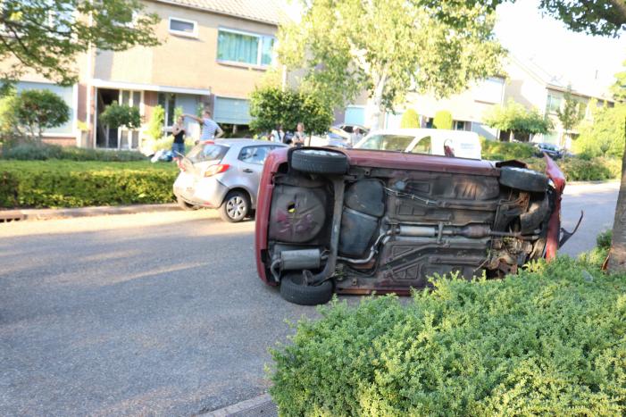 Bestuurder raakt onwel, botst op geparkeerde auto en belandt op zijn kant