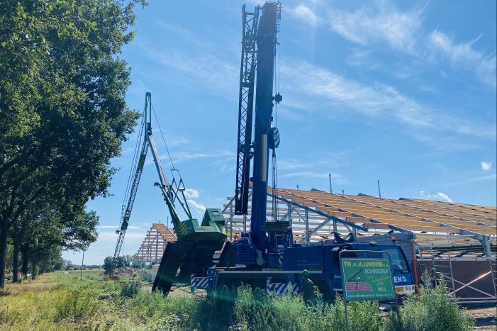 Bouwkraan achter stal omgevallen