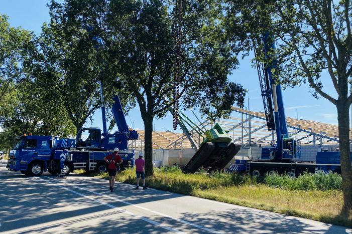 Bouwkraan achter stal omgevallen