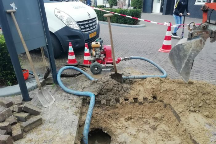 Straat opengebroken door gesprongen waterleiding