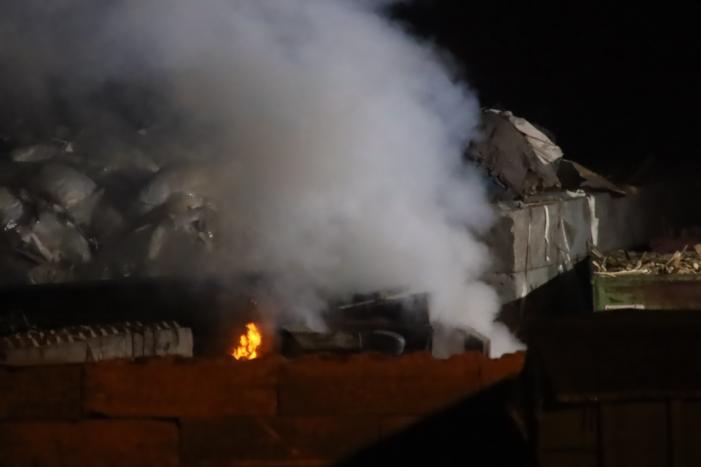 Grote berg afvalhout in brand naast houtopslag