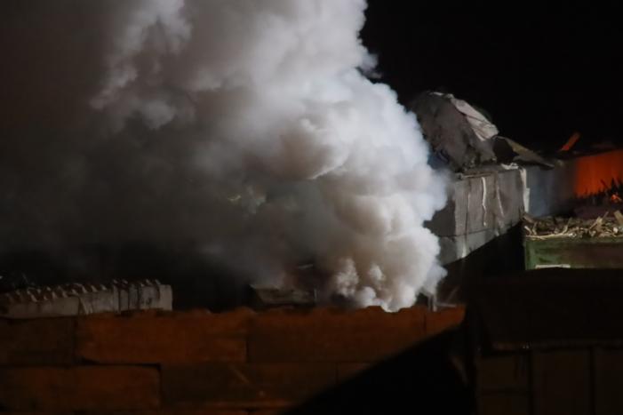 Grote berg afvalhout in brand naast houtopslag